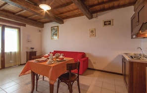A dining area with a table set for two, a red sofa, and a kitchen area with a sink and cabinets.