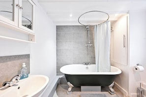 A bathroom with a freestanding bathtub, a sink, and a shower area. - Spacious and bright just-renovated flat with patio (London)