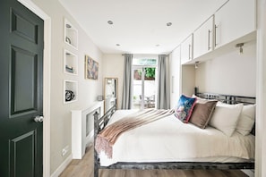 A bedroom with a bed, a fireplace, a window with curtains, and a door. - Spacious and bright just-renovated flat with patio (London)