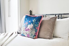 A bed with two pillows, one with a floral pattern and the other plain.