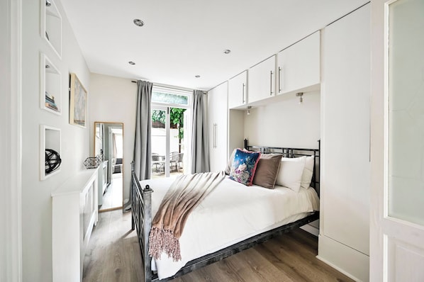 A bedroom with a bed, a wardrobe, a mirror, and a view of an outdoor area.