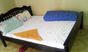 A bed with a wooden frame, a white mattress, and two pillows.