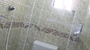 A small, tiled bathroom with a toilet, a shower, and a window. - Crestone Peak Inn Guest House (Nairobi)