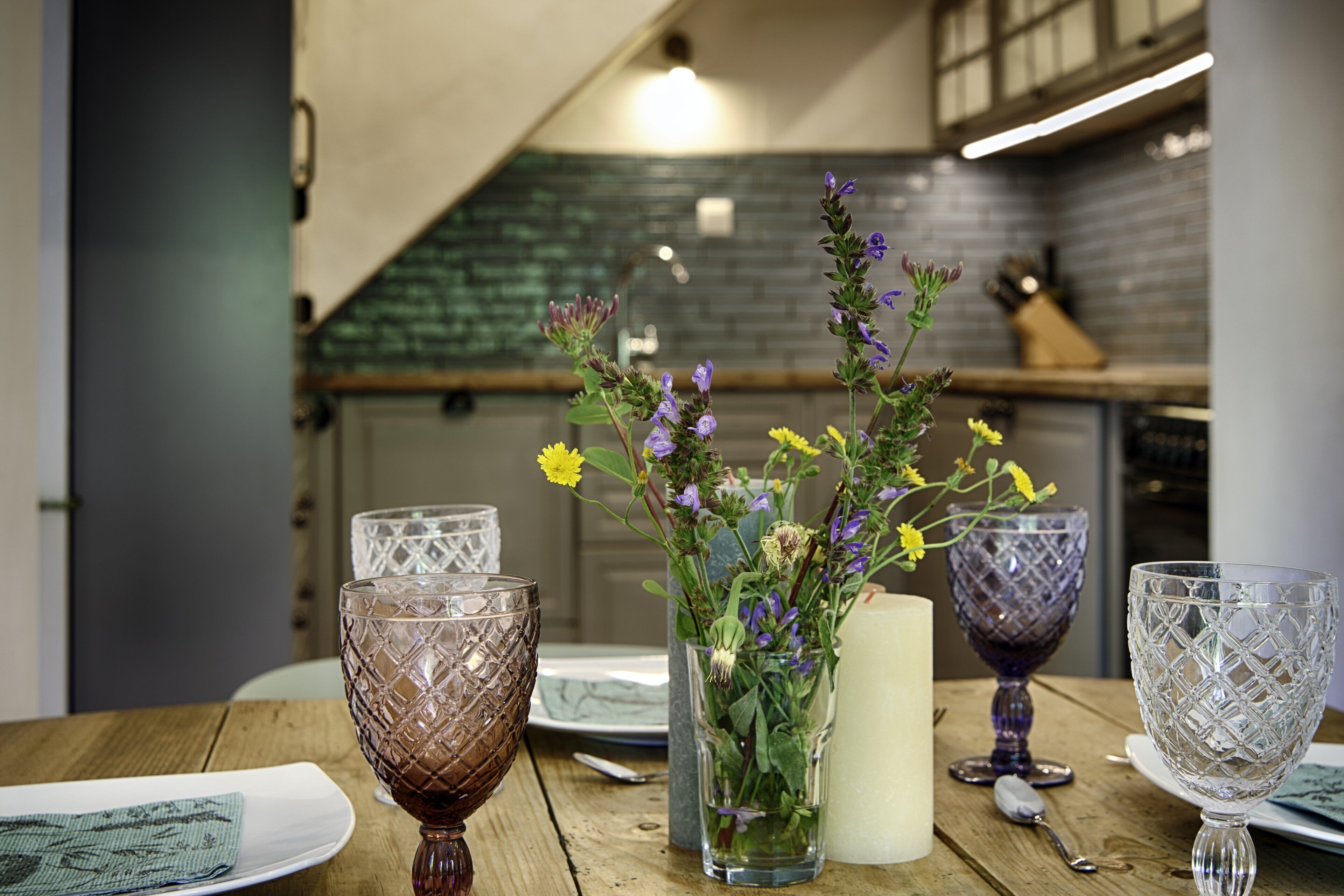 Una mesa de madera con un jarrón de flores y cristalería.