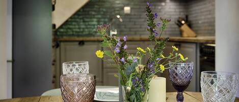 Una mesa de madera con un jarrón de flores y cristalería.