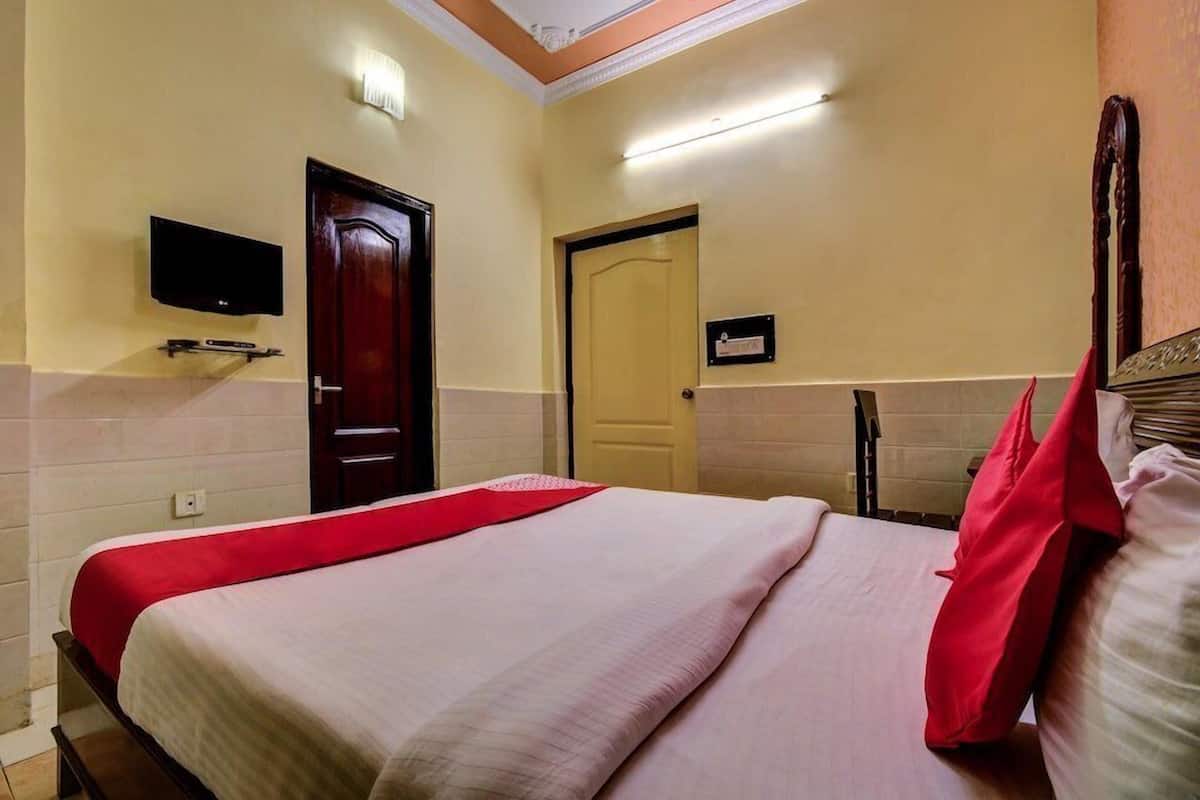 Una habitación de hotel con una cama, un televisor montado en la pared, una puerta y un cartel sobre la puerta.