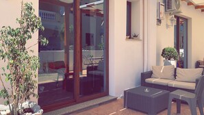 Un patio con porta scorrevole in vetro, mobili in vimini e piante in vaso.