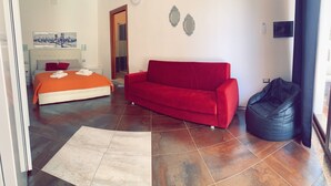 Una camera da letto moderna con un letto, un divano rosso e un pouf nero.