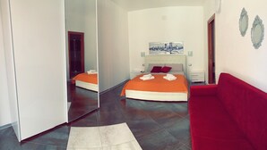 Una camera da letto moderna con un letto grande, un divano rosso e un quadro appeso al muro.