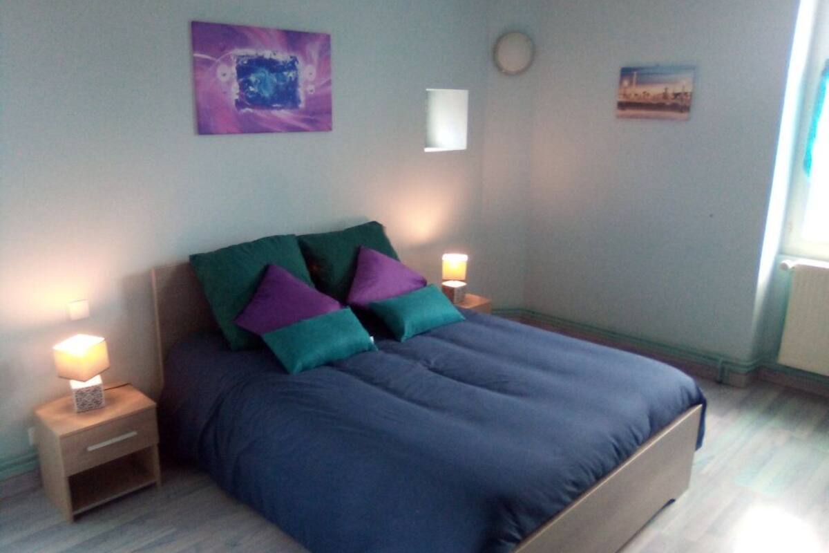 A bedroom with a bed, two bedside tables with lamps, and wall art.
