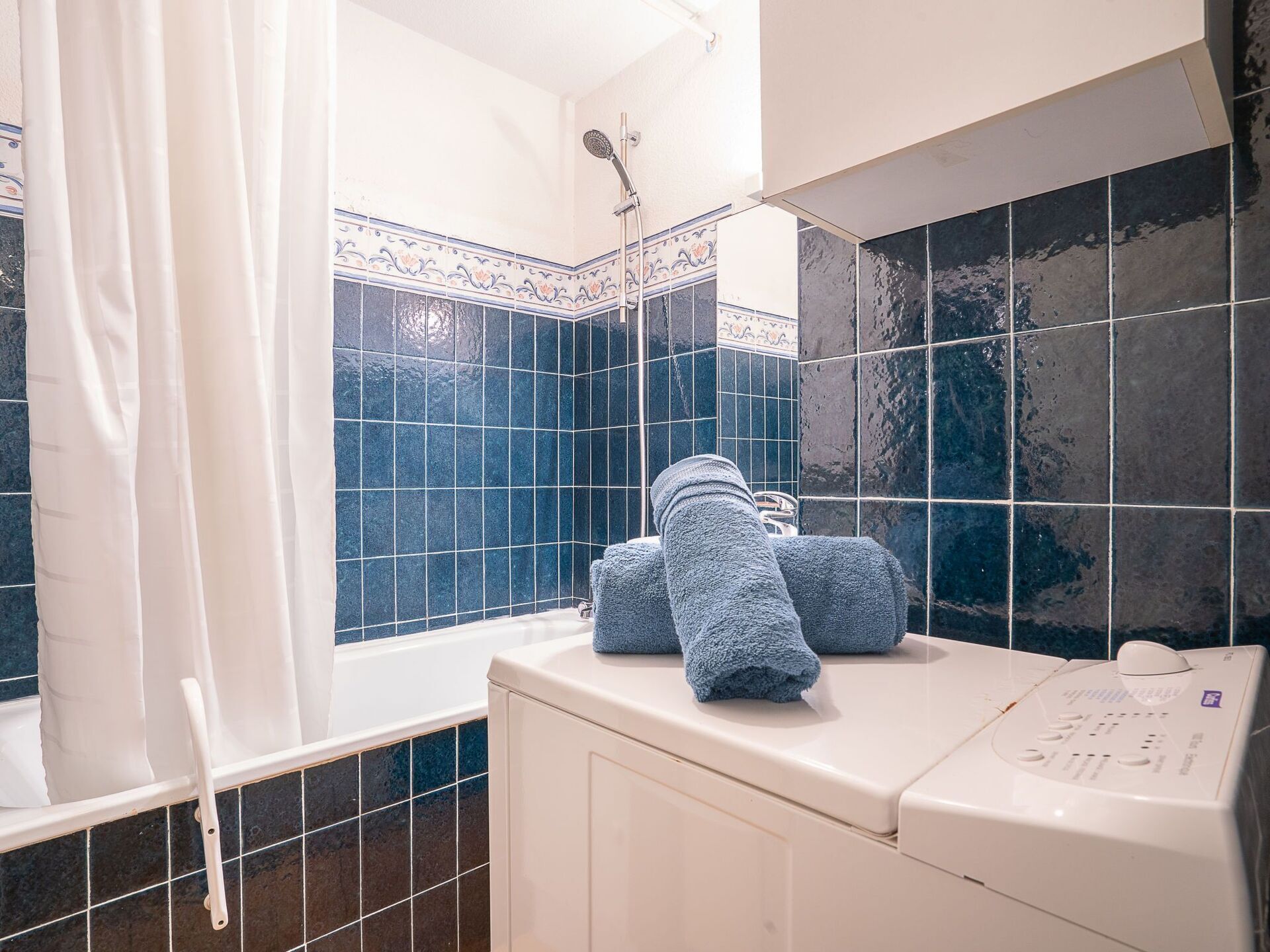 Ett badrum med badkar, dusch och en vit tvättmaskin.