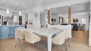 A spacious kitchen with white cabinetry, a central island, and a dining area with wicker chairs.