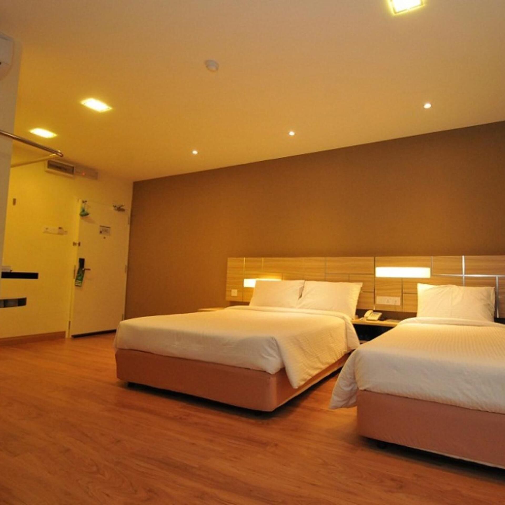A hotel room with two beds, wooden flooring, and a modern design.