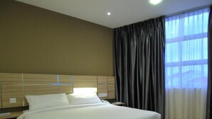 Ett hotellrum med en stor säng, ett träbeklätt sänggavel och utsikt över staden genom fönstret.
