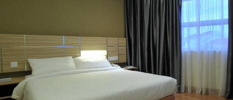 Habitación de hotel con una cama grande, cabecero de madera y vistas a la ciudad por la ventana.