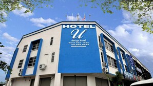 Ett hotell med en framträdande blå och vit fasad, en stor skylt med texten ”HOTEL” och kontaktuppgifter som visas.
