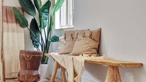 A cozy corner with a wooden bench, a woven rug, a rustic stool, and a large plant. - Miami Toro: Private Pool, Pool Table, & Near Beach (Miami)