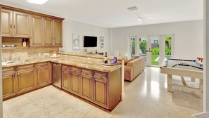 A modern kitchen with wooden cabinets, a marble countertop, and a built-in dishwasher. - Miami Toro: Private Pool, Pool Table, & Near Beach (Miami)