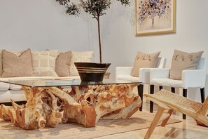 Ein modernes Wohnzimmer mit einem Glastisch, weißen Sofas und einem auffälligen Holzboden.