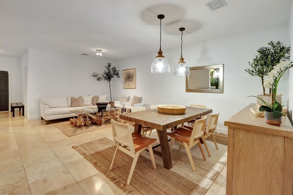 Ein geräumiges Wohnzimmer mit Holzesstisch, weißem Sofa und einem großen Spiegel.