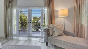 A living room with a sofa, a lamp, and a view through a sliding door to an outdoor area with greenery. - Miami Toro: Private Pool, Pool Table, & Near Beach (Miami)
