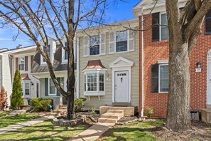 A row of townhouses with a central entrance, a small front yard, and a tree. - ClintonCrest: Private Yard & Near DC (Sterling)