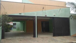 Un edificio con entrada verde, zona de estacionamiento techada y portón negro.