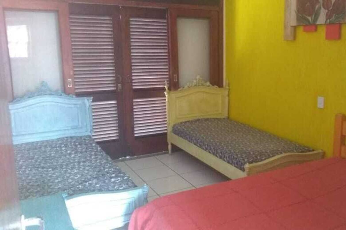 Une petite pièce avec un lit, un banc et une porte avec des volets.