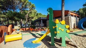 A playground with a dinosaur play structure, a yellow slide, and a blue climbing area. - 4 * apartments superior / 2pax studio-l (Zaton)