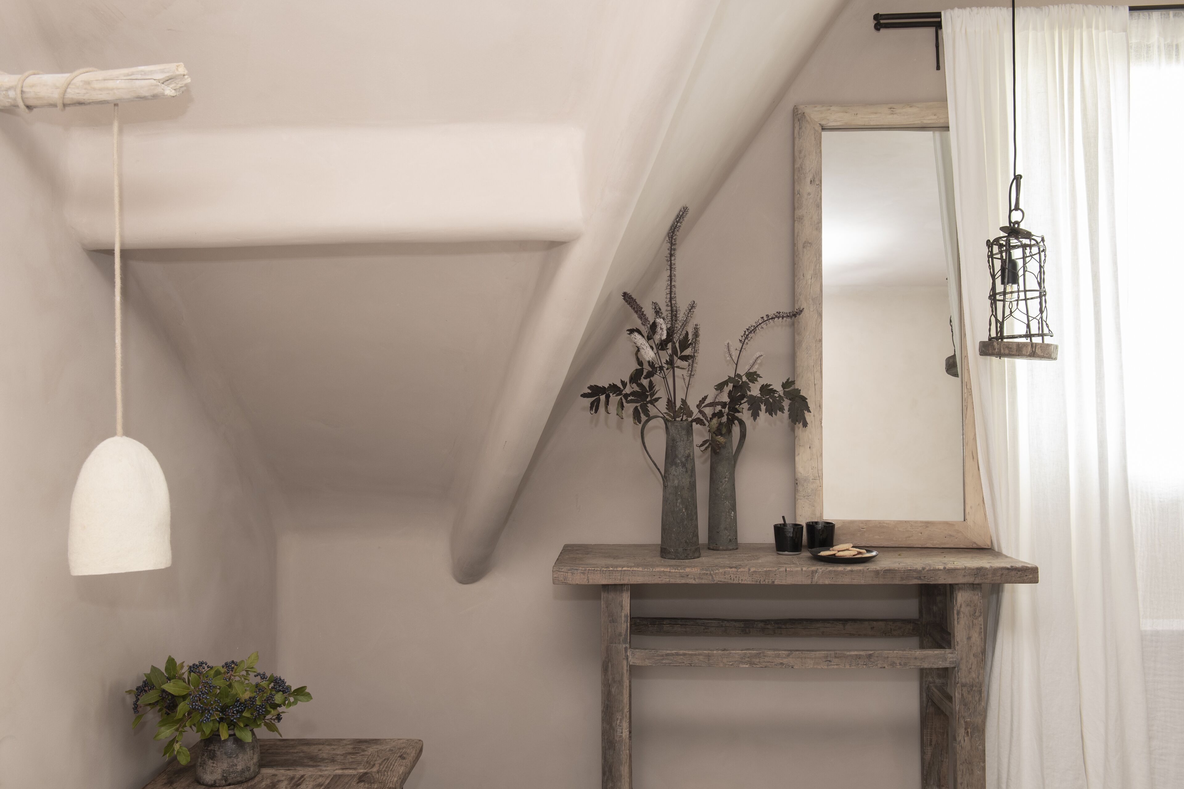 A rustic interior with a wooden console table, a hanging light fixture, and a mirror.