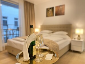 A hotel room with a bed, a bedside table with a lamp, a window with curtains, and a balcony. - Steiner Residences Vorgartenstrasse (Vienna)