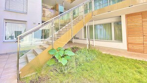 A multi-level residential building with a glass staircase, outdoor seating area, and a garden. - Steiner Residences Vorgartenstrasse (Vienna)