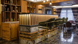 Un área de bar con estantes de madera, una barra de mármol y taburetes de bar modernos.