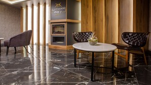 Un lobby moderno con piso de mármol, sillas de cuero, una mesa redonda y una pared de acento de madera con el nombre del hotel.