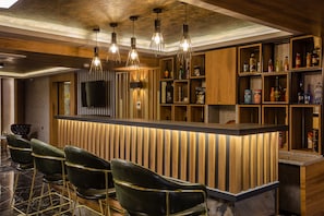 A bar area with wooden shelves, a television, and bar stools. - Kayhan City Hotel (Bursa)
