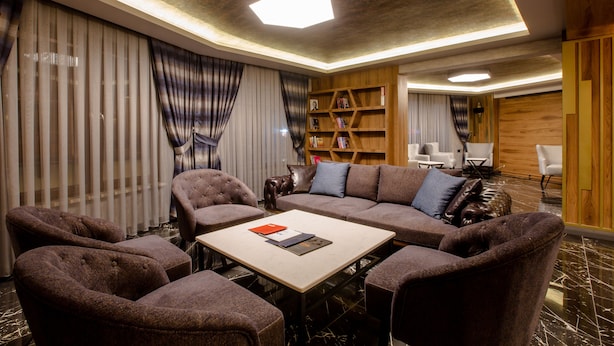 Una sala de estar moderna con un sofá seccional, sillones, una mesa de centro y una estantería de madera.