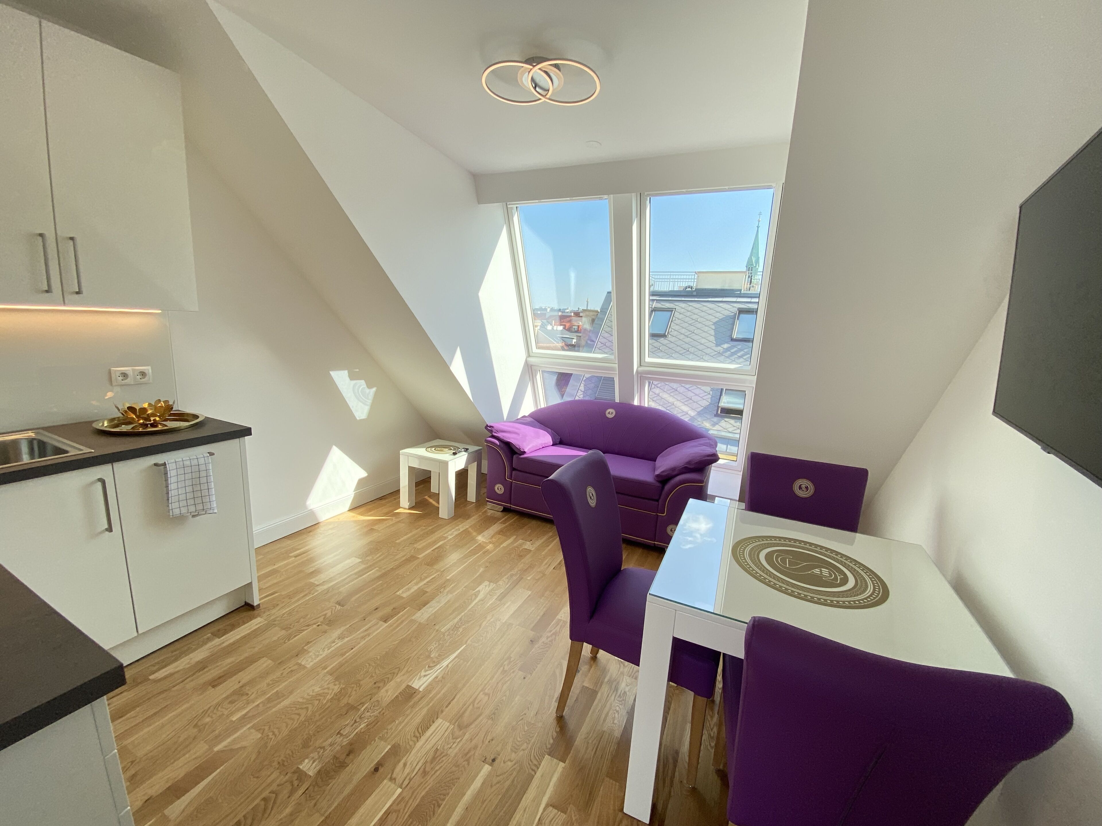 A modern loft apartment with a kitchen, dining area, and large windows offering city views.