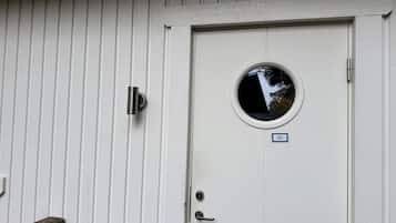 Una puerta blanca con un ventanal redondo, un timbre y una pequeña placa con el número 20.