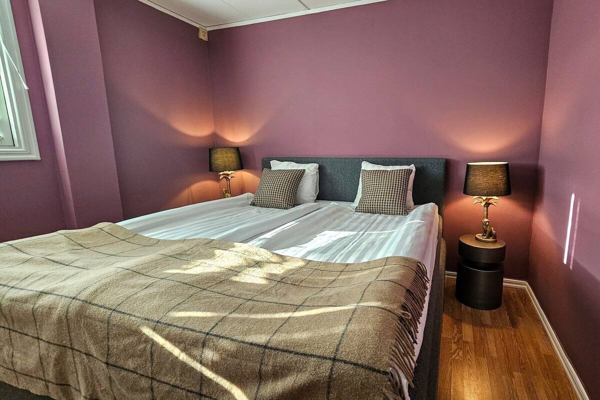 Une chambre avec deux lits, une couverture à carreaux, deux lampes et une table de chevet.