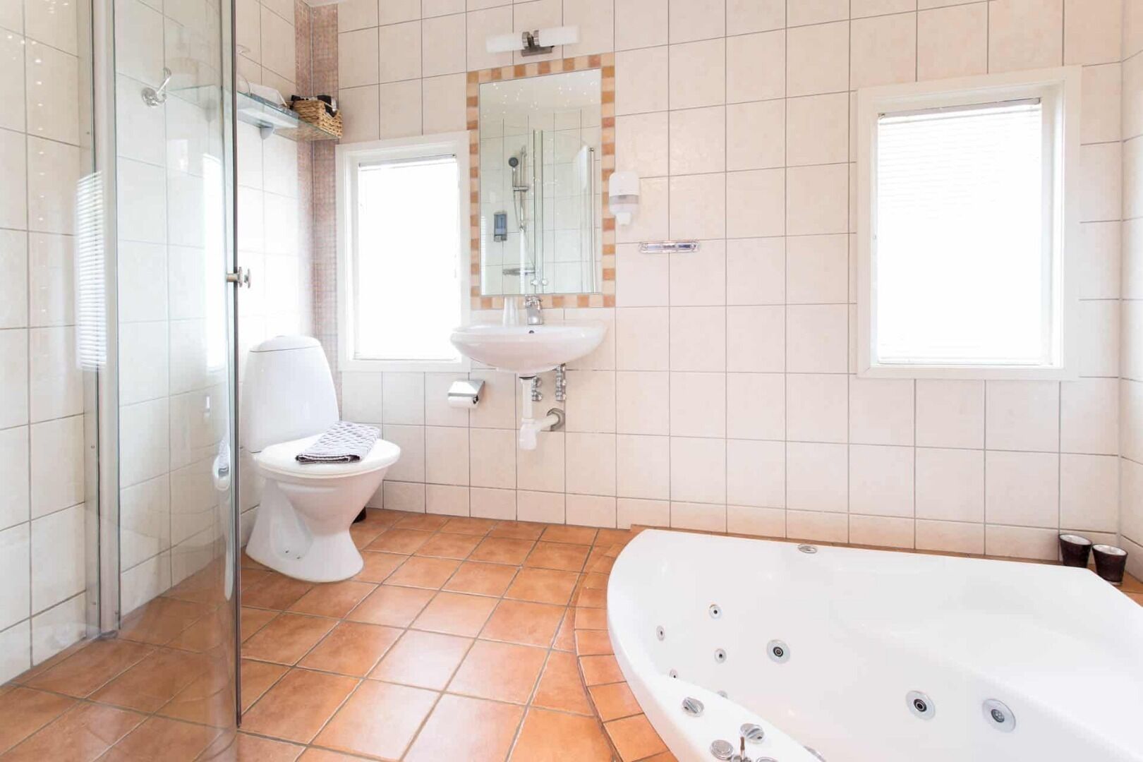 A bathroom with a glass shower enclosure, a toilet, a sink, and a bathtub.