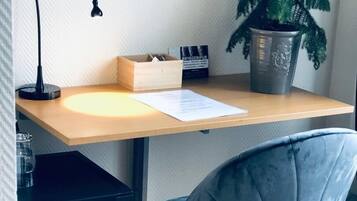 A workspace with a wooden desk, a black lamp, a grey chair, a potted plant, and a Dometic coffee machine.