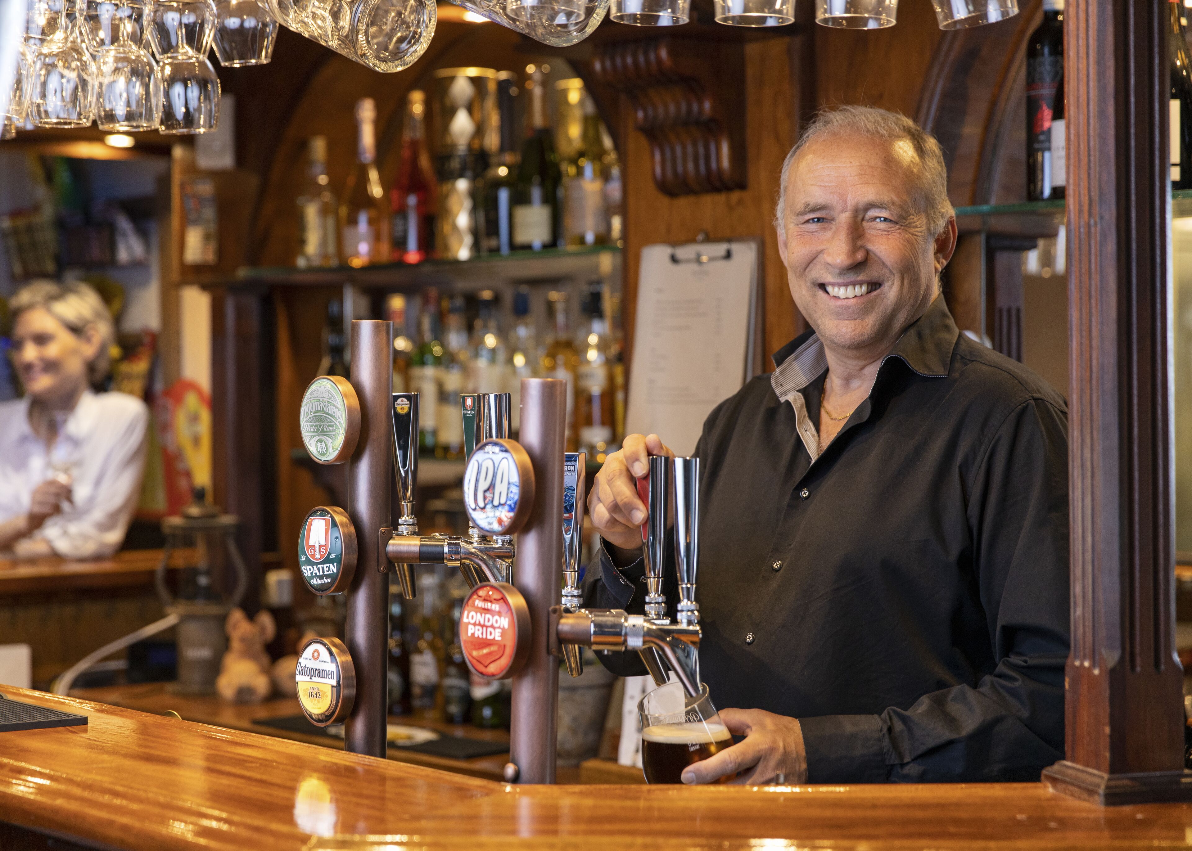 A bar with multiple beer taps and a person holding a beer glass.