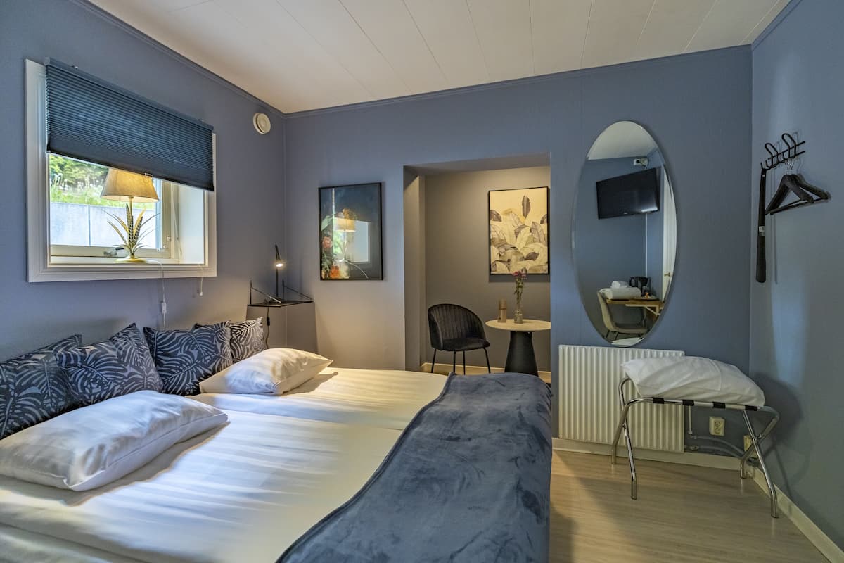 Une chambre d’hôtel avec un grand lit, un bureau, une chaise, un miroir et un radiateur.