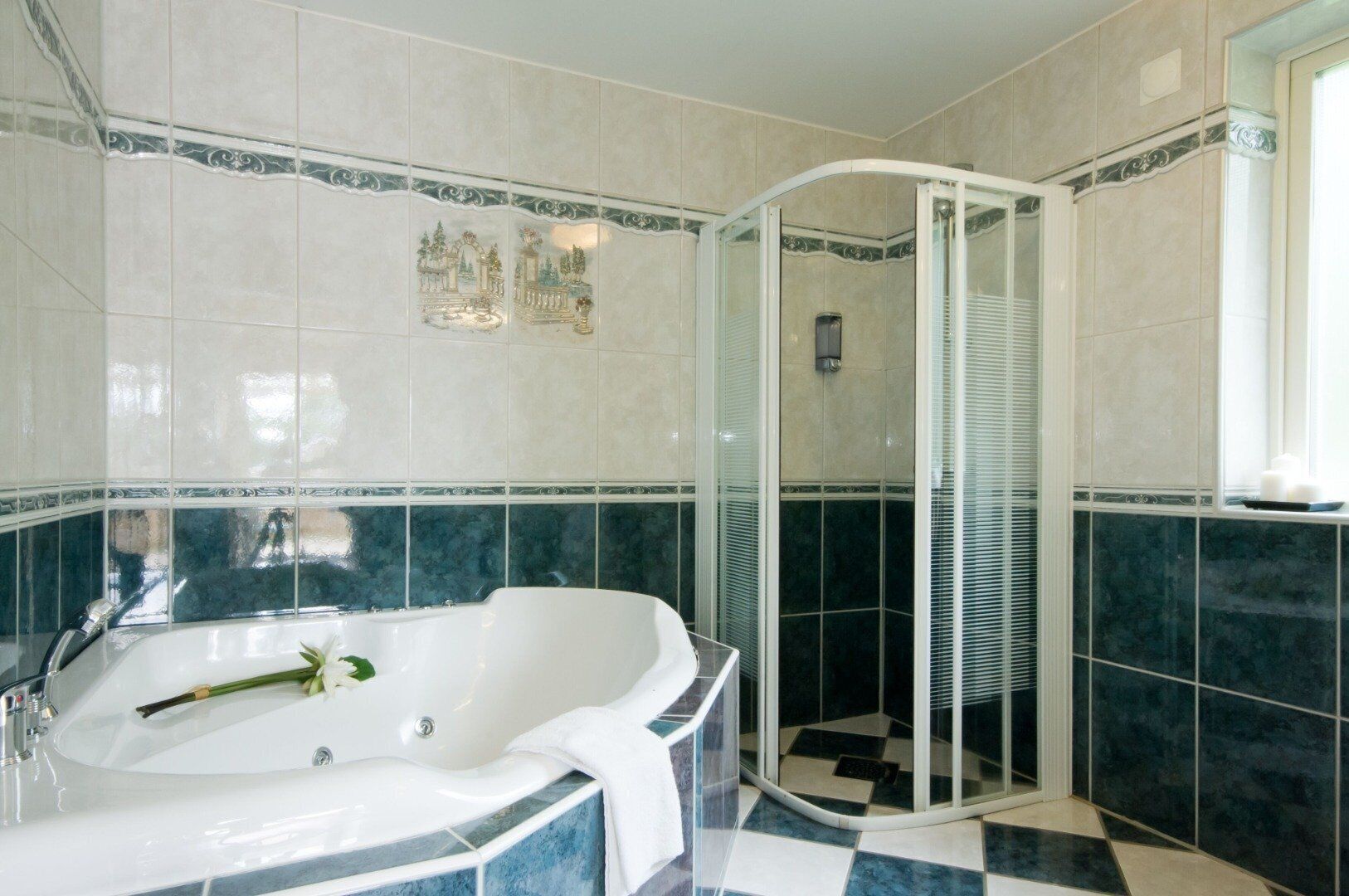 A bathroom with a freestanding bathtub, a glass-enclosed shower, and decorative wall tiles.