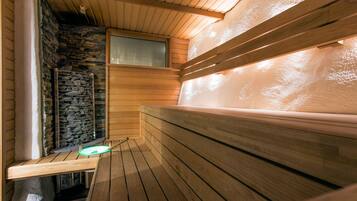 A sauna with wooden benches, a stone wall, and a window.
