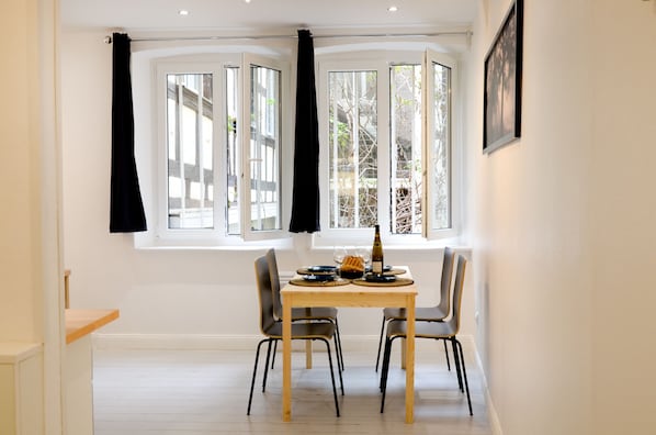 A dining area with a table set for two, a bottle, and a glass.