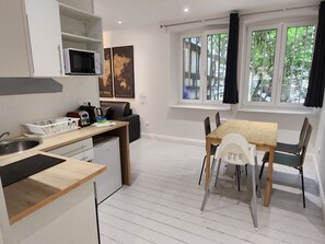 Une cuisine compacte équipée d’un évier, d’un four à micro-ondes et d’un coin repas avec des chaises et une table.