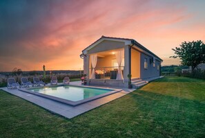 Una casa moderna amb piscina i zona de seients a l'exterior.