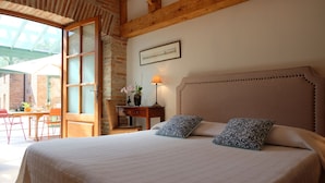 Ein Schlafzimmer mit einem großen Bett, einem Holz-Kopfteil, einem Schreibtisch mit Stuhl und einem Fenster mit Blick nach außen.