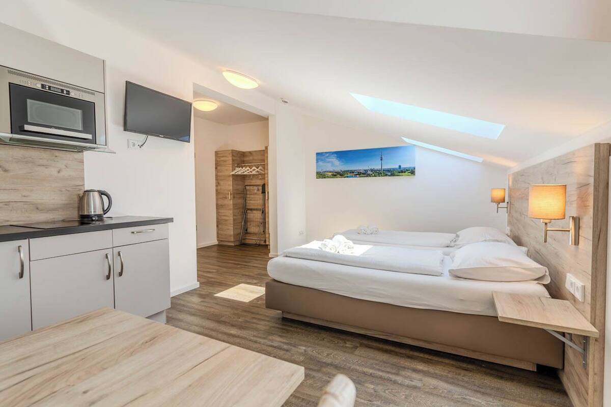 A modern bedroom with a bed, bedside tables, a TV, and a painting of a cityscape.